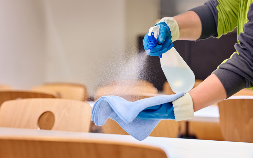 Pflegekraft mit Sprühflasche und Lappen