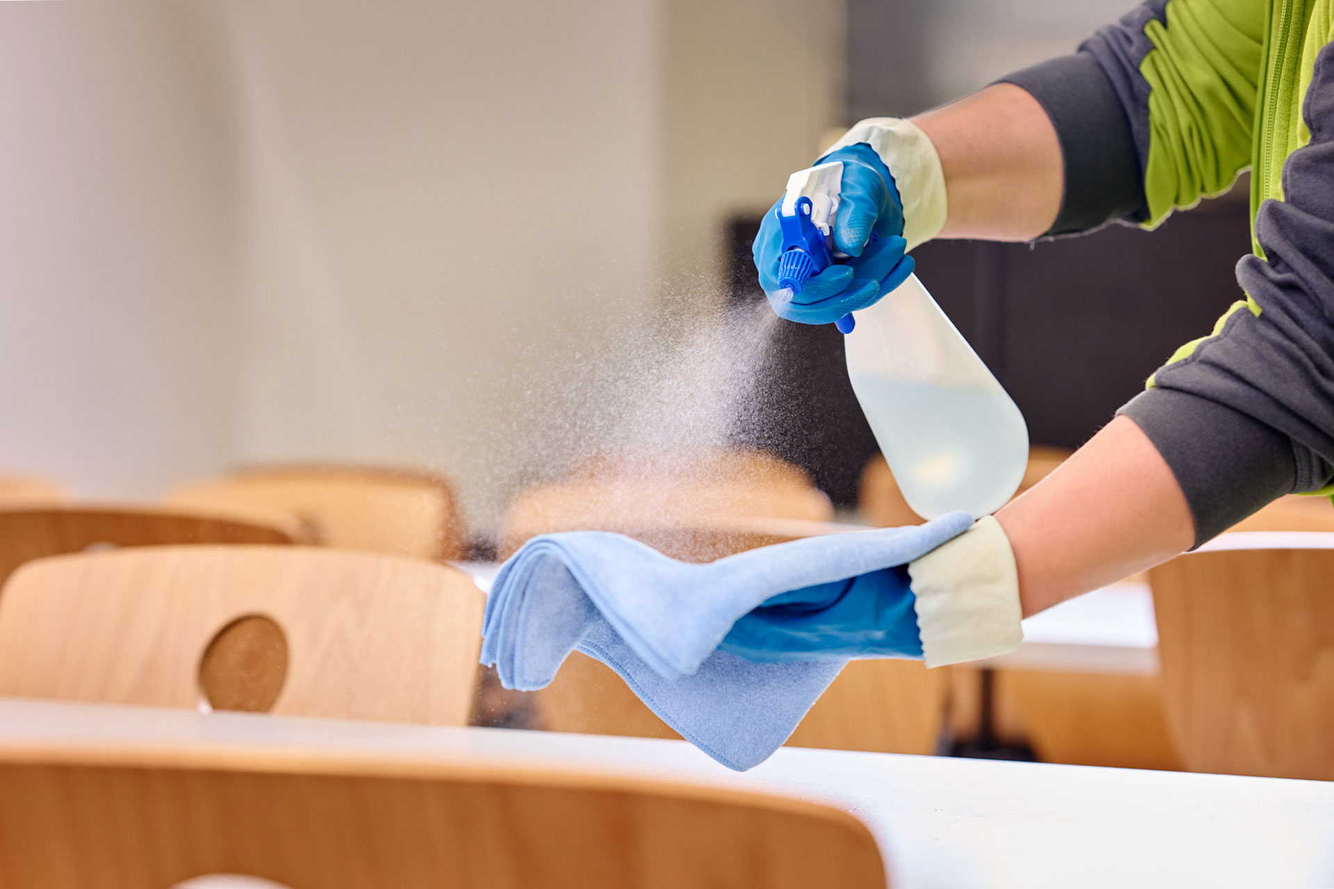 Pflegekraft mit Sprühflasche und Lappen